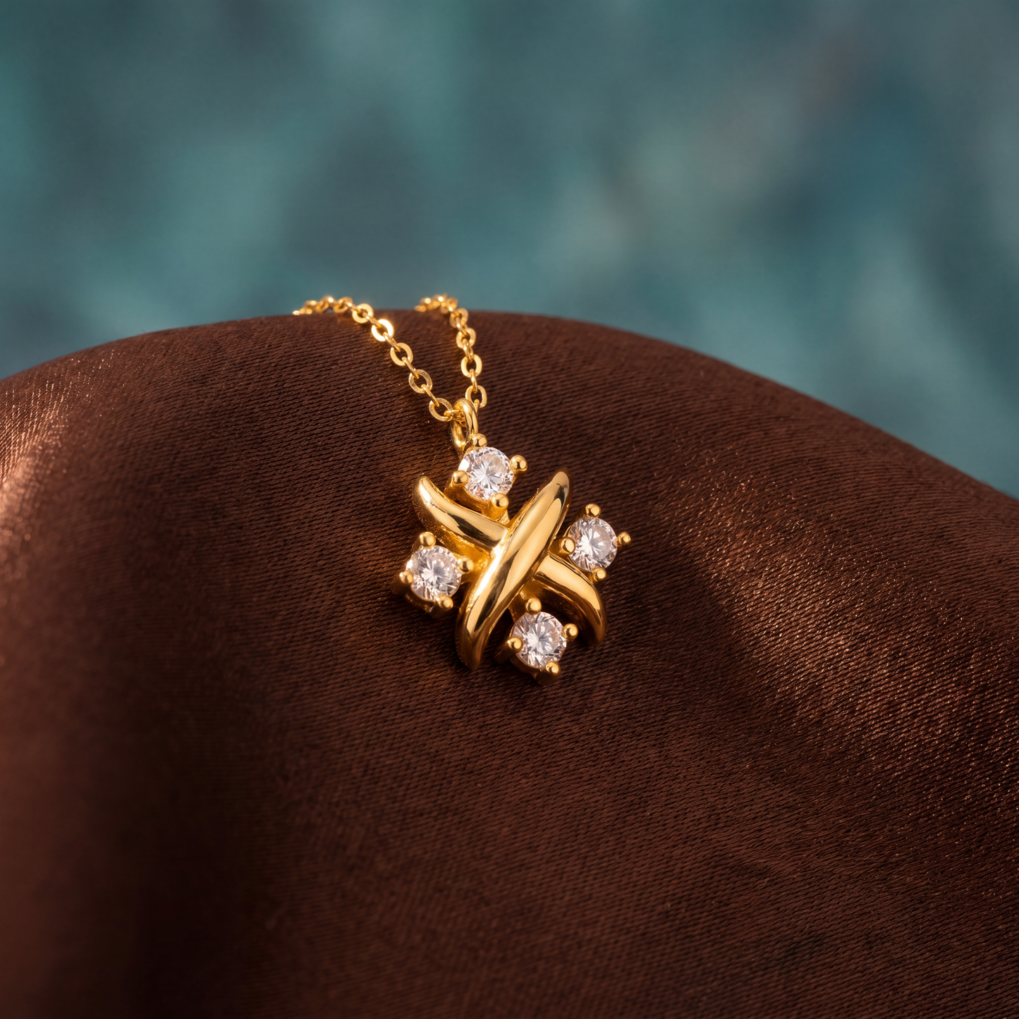 Gold necklace with a star-shaped pendant on a brown cushion against a teal background