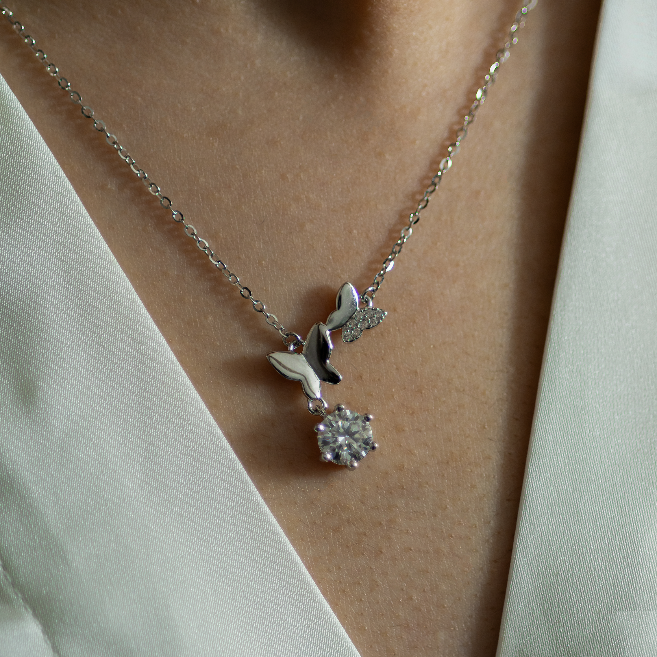 Silver necklace with a pendant on a person wearing a white blouse