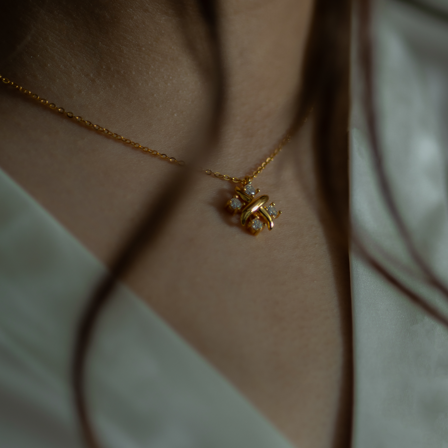 Gold necklace with a butterfly pendant on a person wearing a light green top.