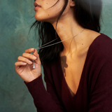 Woman wearing a deep neckline top against a textured teal background