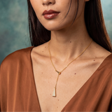 Woman wearing a gold necklace against a textured blue background