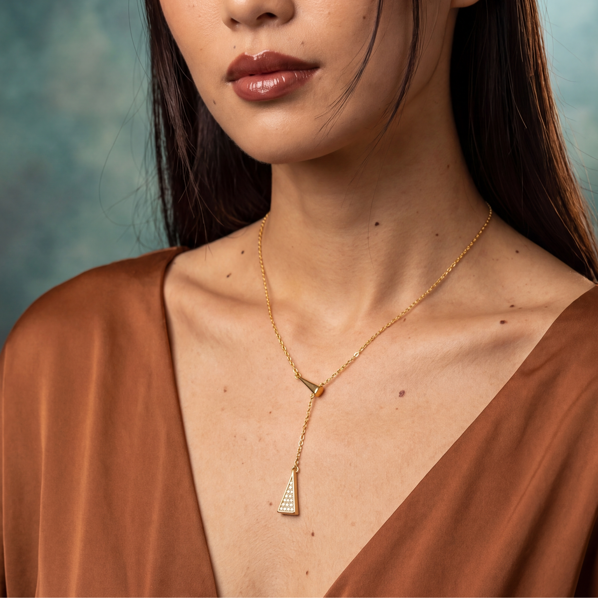 Woman wearing a gold necklace against a textured blue background