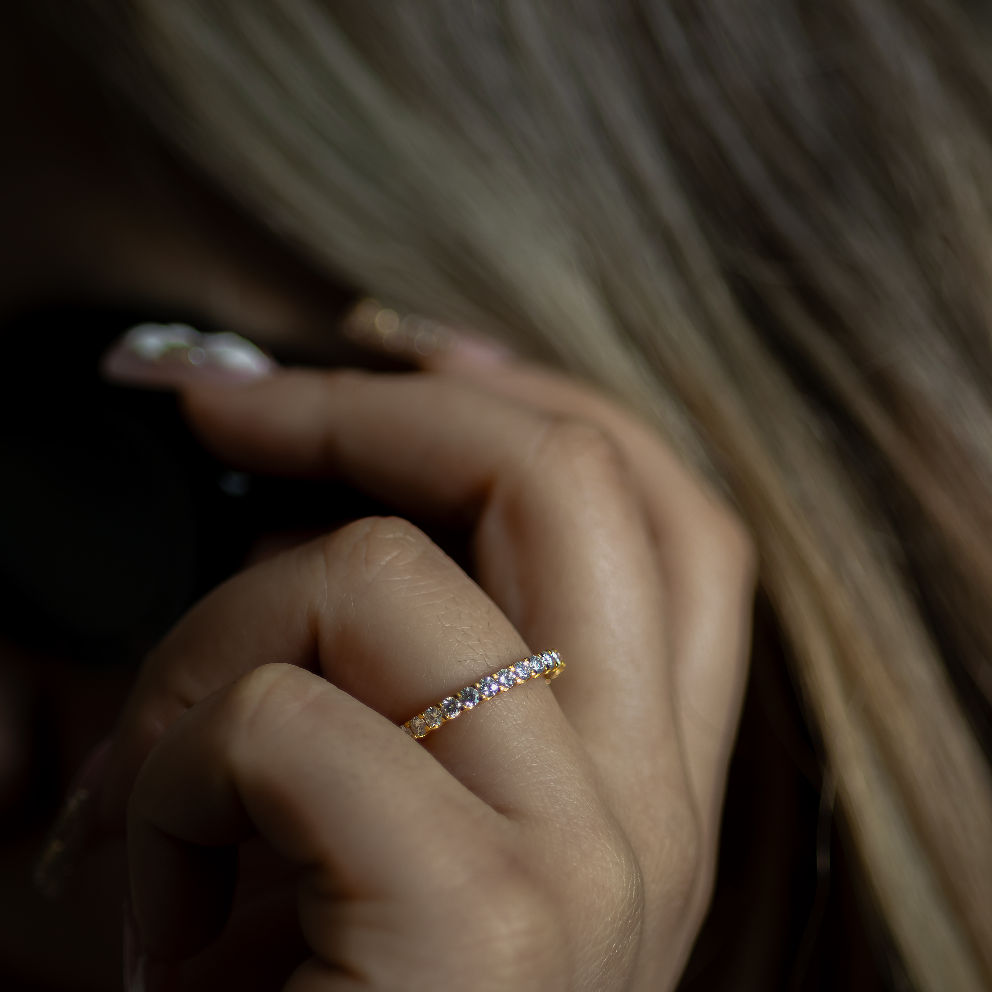 Close-up of a hand wearing a diamond ring with blurred background