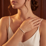 Woman wearing a gold bracelet with a neutral background