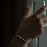 Hand wearing a bracelet with a glass in the background