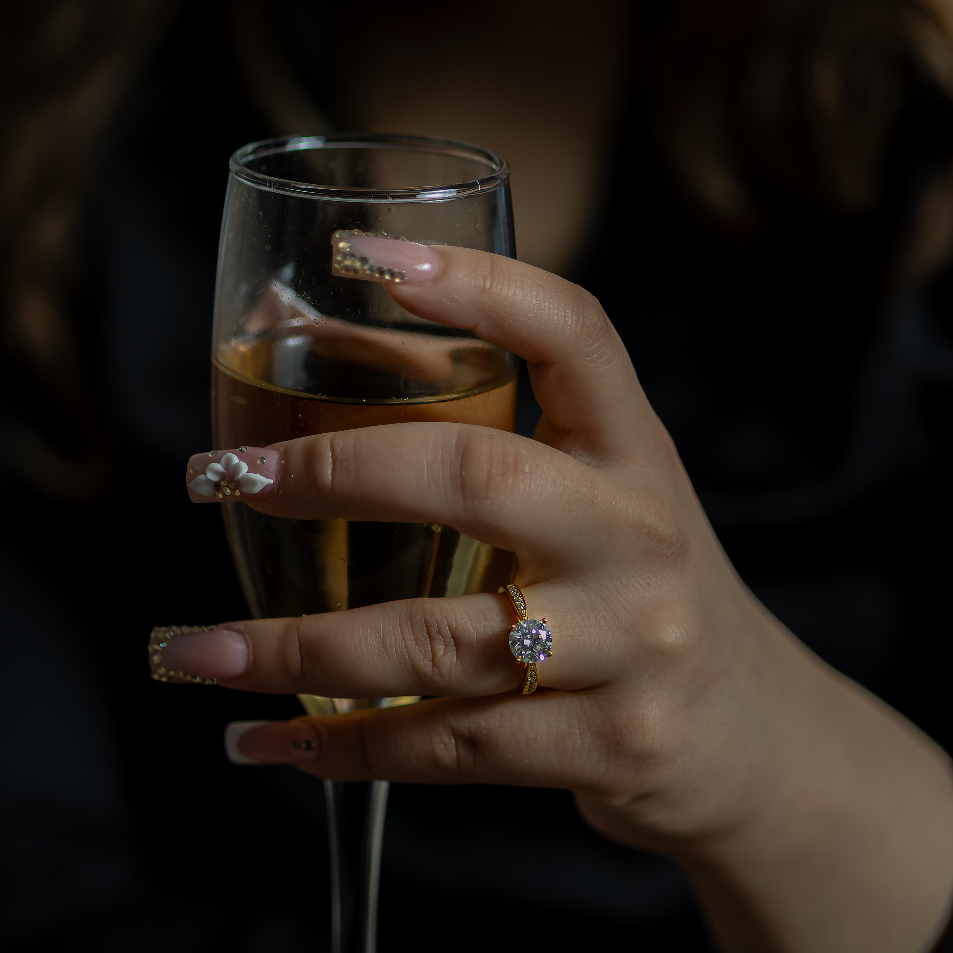 Hand holding a glass of champagne with a blurred background