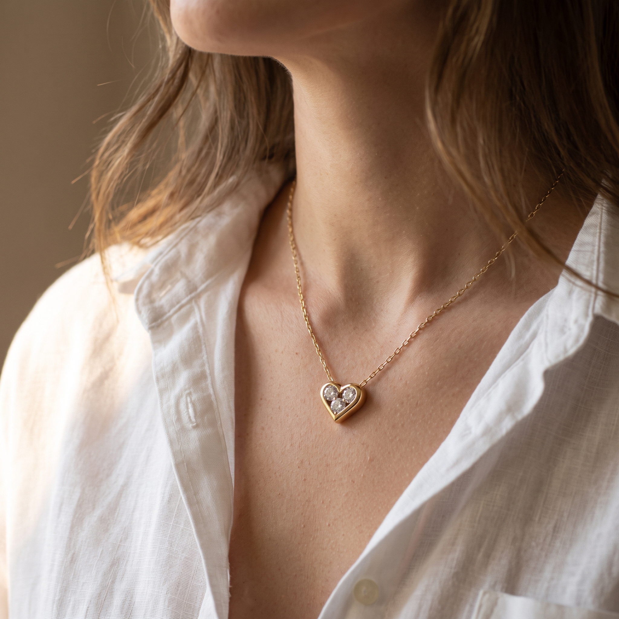 The MOHRA Petite Heart Pendant on a delicate gold chain, worn at the collarbone