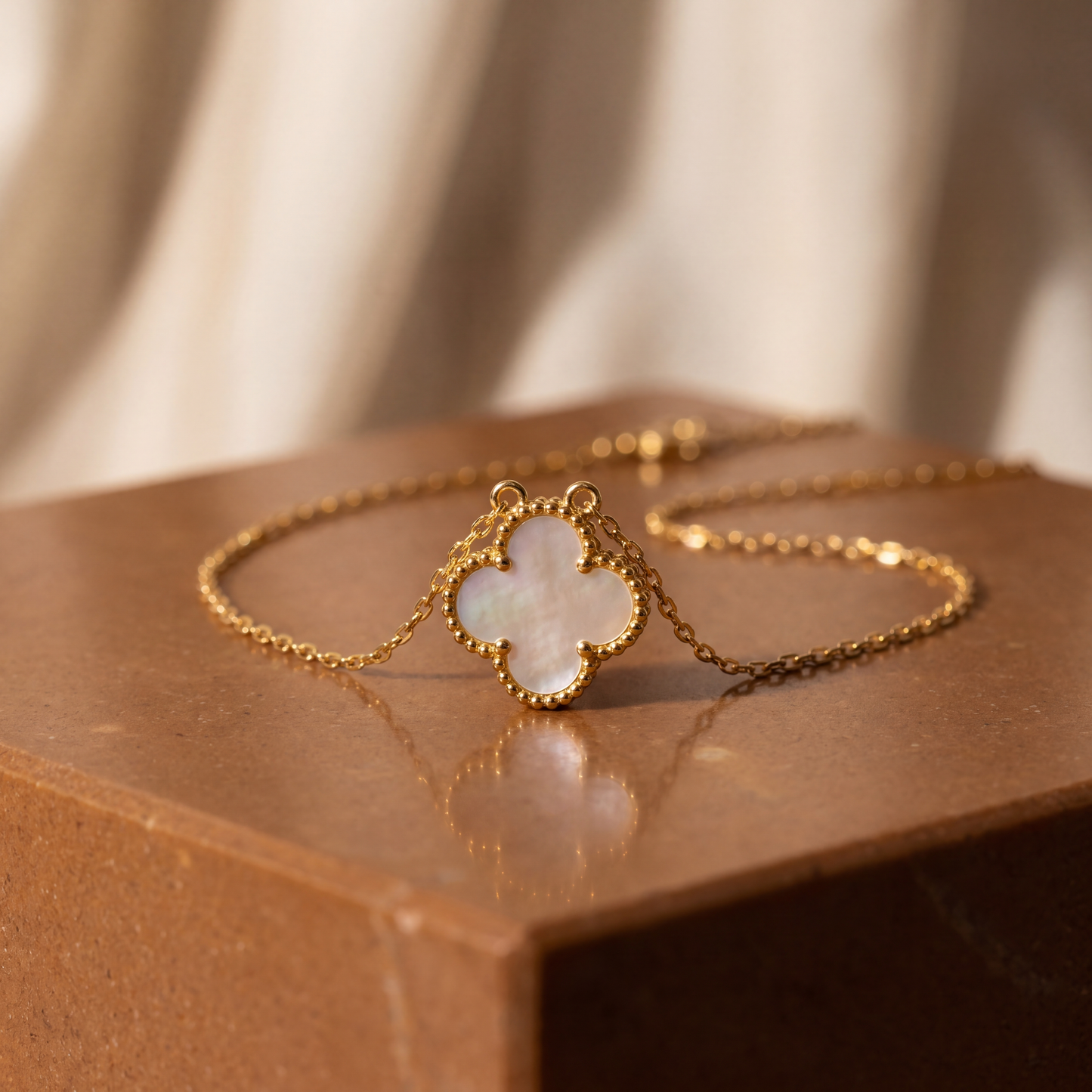 Gold bracelet with a clover-shaped opal stone on a brown surface