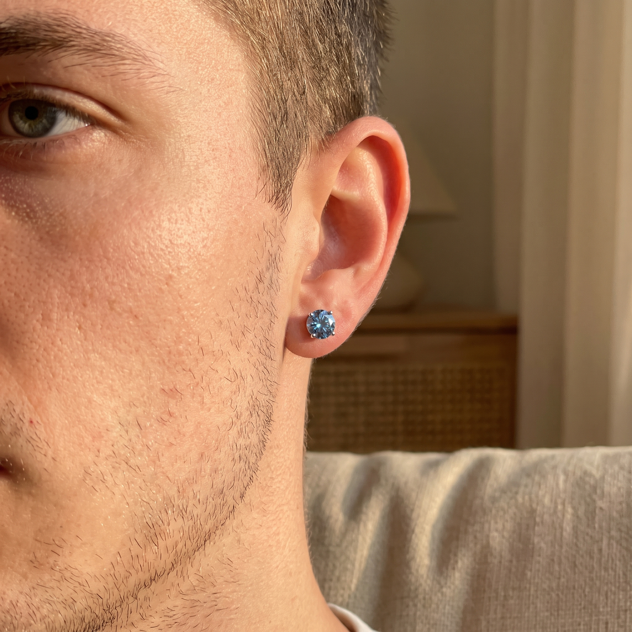 The MOHRA Blue Moissanite Stud earring worn, blue solitaire in a four-prong setting