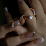 Woman wearing a ring with a diamond against a dark background