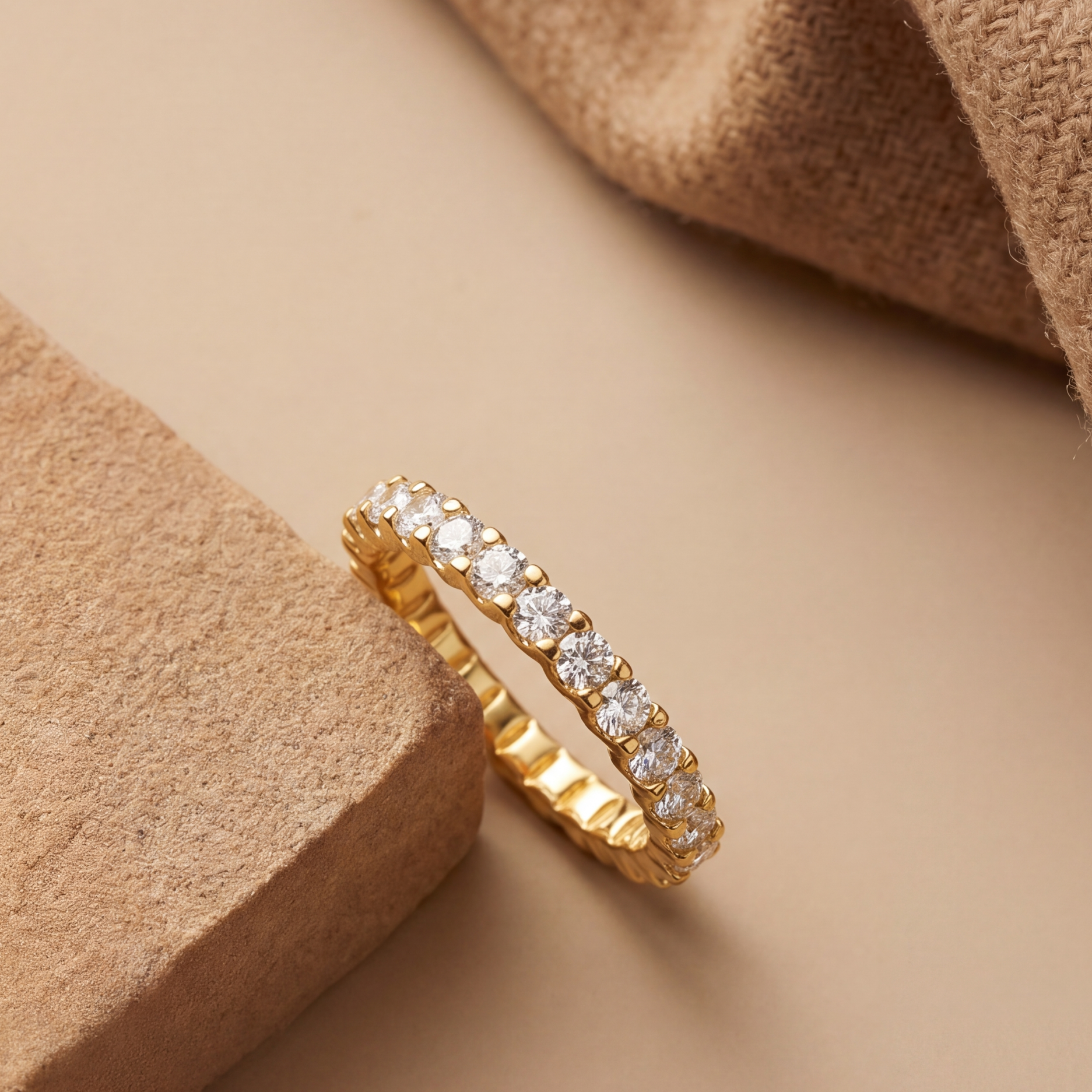 Gold ring with diamonds on a beige surface with textured elements