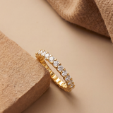 Gold ring with diamonds on a beige surface with textured elements