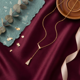 Gold necklace with a pendant on a burgundy fabric background