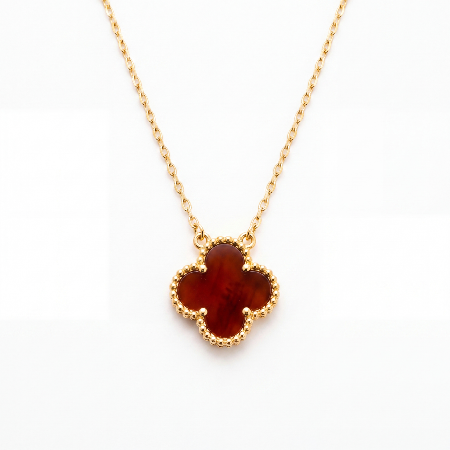 Gold necklace with a clover-shaped amber pendant on a white background