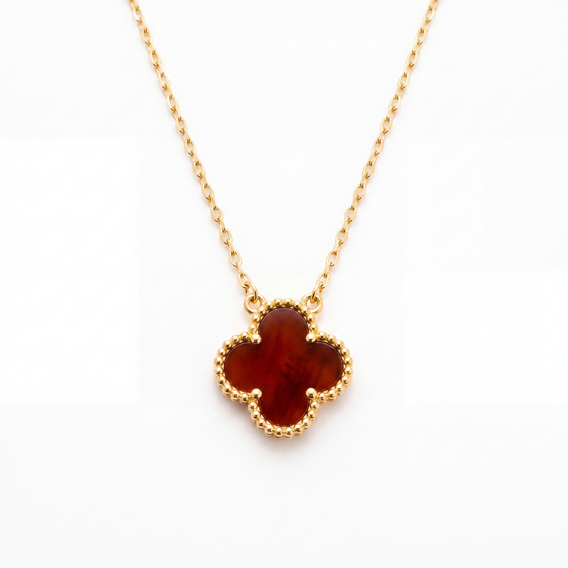 Gold necklace with a clover-shaped amber pendant on a white background