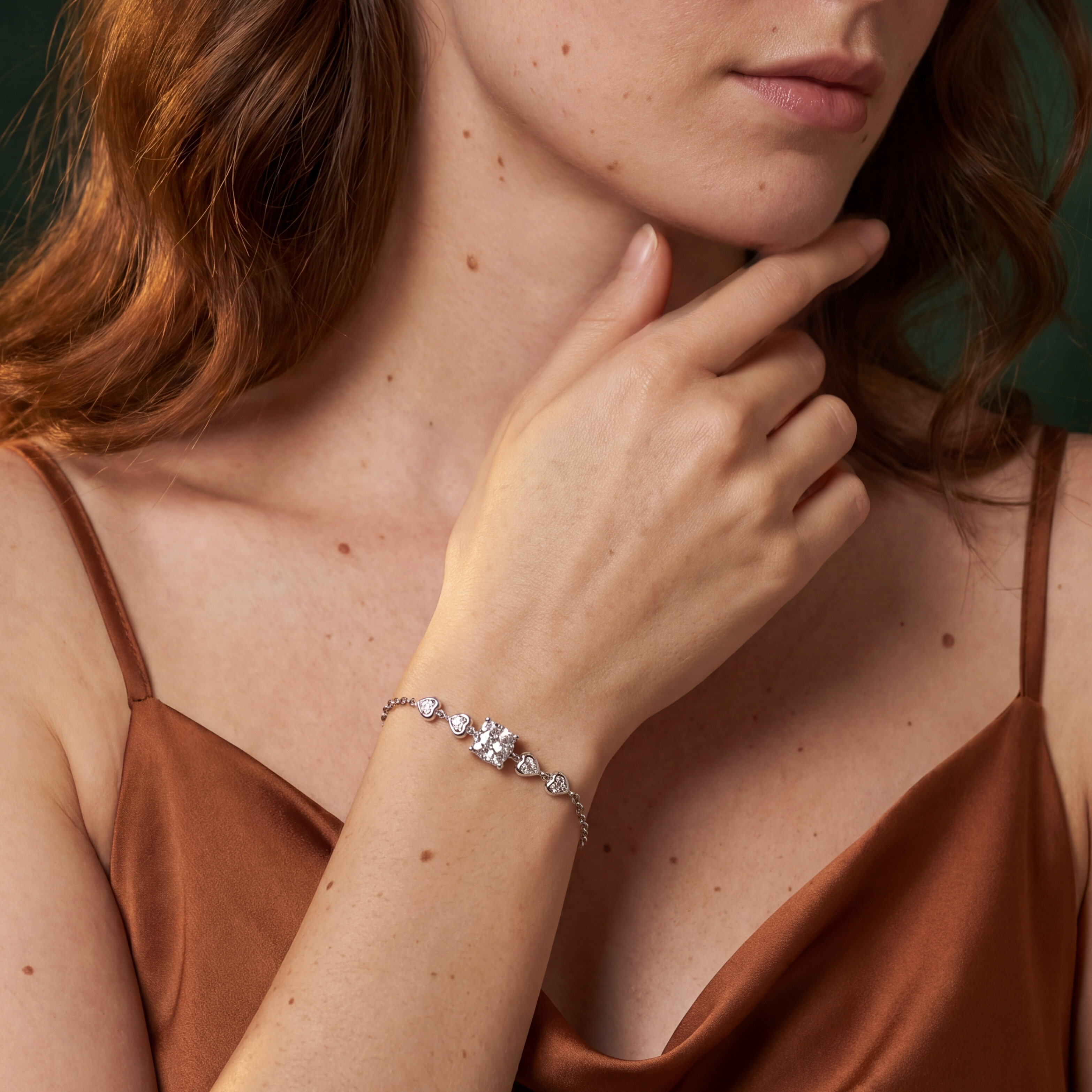 Woman wearing a brown top and bracelet with a dark green background