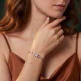 Woman wearing a brown top and bracelet with a dark green background