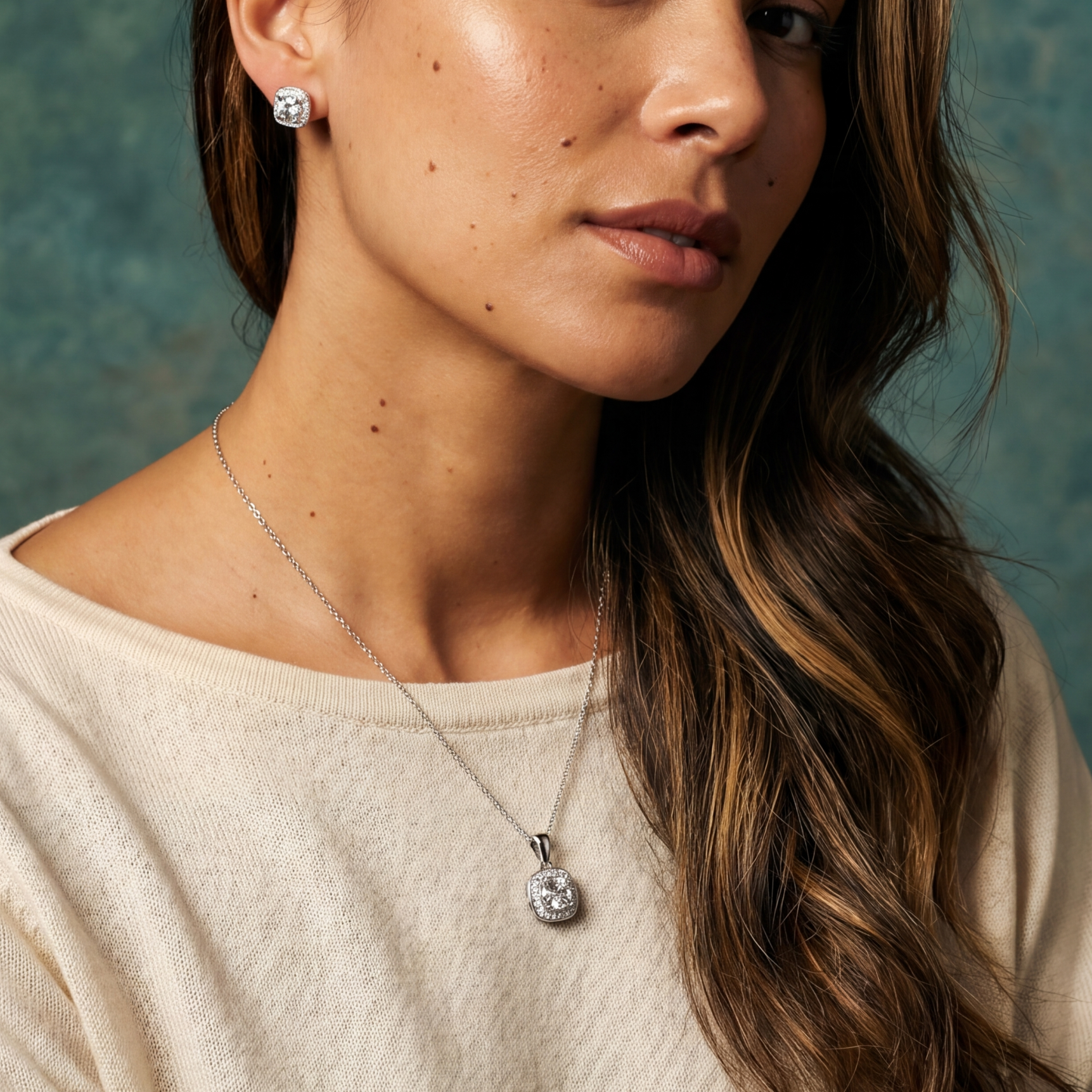 Woman wearing a necklace with a pendant against a textured green wall.