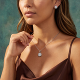 Woman wearing a diamond necklace and earrings against a teal background