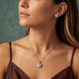 Close-up of a woman wearing a diamond necklace and earrings against a neutral background