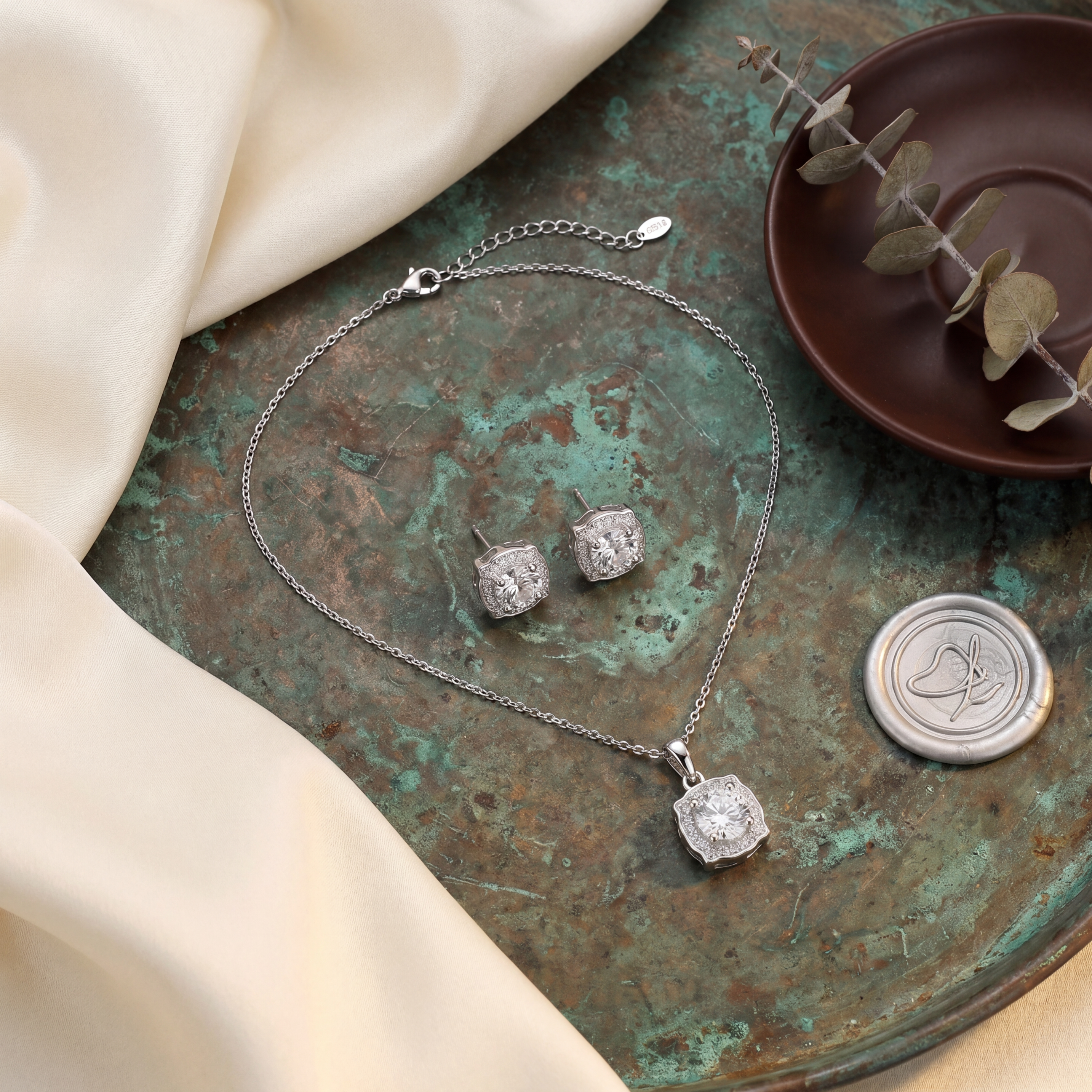 Silver jewelry set with necklace and earrings on a textured surface