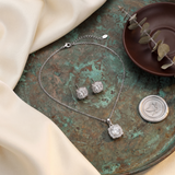 Silver jewelry set with necklace and earrings on a textured surface