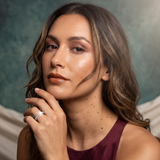 Woman with hand on chin against a textured wall background